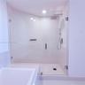 Walk-in shower featuring a frameless glass enclosure, rainfall showerhead, handheld shower attachment, integrated wall niche, and tile flooring