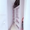 Built-in, floor-to-ceiling white shelving with adjustable cabinetry and light-toned wood-finish flooring