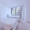 Floor-to-ceiling glass sliding doors, private balcony, and light-toned wood-finish flooring