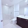 Bathroom featuring a glass-enclosed walk-in shower, dark-toned vanity with a light-colored countertop, integrated rectangular sink, and floor-to-ceili