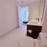 Bathroom featuring a dark wood-finish vanity with dual rectangular vessel sinks, light-toned stone countertop, polished tile flooring, and large-forma