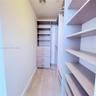 Walk-in closet featuring built-in shelving, four pull-out drawers with metallic hardware, integrated hanging rods, and wood-finish flooring
