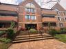 Multi-story brick exterior featuring arched windows, a paved walkway, and tiered stone entrance steps with metal railings