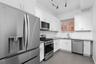 Kitchen featuring white shaker-style cabinetry, solid-surface countertops, subway tile backsplash, stainless steel appliances, and large-format tile f