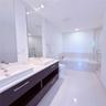 Dual vanity with rectangular vessel sinks and stone-composite countertop, dark wood-finish cabinetry, recessed ceiling lighting, tiled soaking tub, an