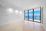 Floor-to-ceiling windows, wood-finish flooring, recessed ceiling lighting, and a private balcony featuring a water backdrop