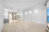 Open-concept space featuring light-toned wood-finish flooring, recessed architectural soffit lighting, glass-enclosed shower, soaking tub, and floor-t