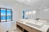 Dual vanity featuring rectangular vessel sinks, light wood-finish cabinetry, quartz countertops, and large wall-mounted mirrors