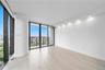 Floor-to-ceiling windows, wood-finish flooring, recessed ceiling lighting, and a private balcony featuring a metal railing