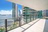 Expansive covered balcony featuring light-toned tile flooring and a glass panel railing