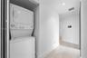 Laundry closet featuring a white stacked washer and dryer unit, light wood-finish flooring, and recessed ceiling lighting