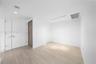 Light-toned wood-finish flooring, white walls, four-bulb track lighting, and solid-core interior doors with modern metallic hardware