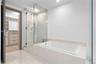 Glass-enclosed walk-in shower with rain showerhead, deep-soaking bathtub with tile surround, built-in custom closet cabinetry, and large-format floor 