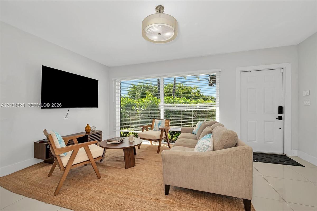 Large format tile flooring, expansive multi-pane window, drum-style ceiling fixture, and a solid six-panel exterior entry door