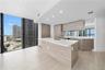 Kitchen featuring wood-finish cabinetry, white countertops, a mirrored backsplash, recessed lighting, and floor-to-ceiling windows