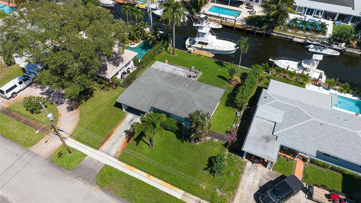 Waterfront property featuring a canal-front bulkhead, private boat slip, paved driveway, and established landscaping