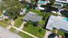 Waterfront property featuring a canal-front bulkhead, private boat slip, paved driveway, and established landscaping