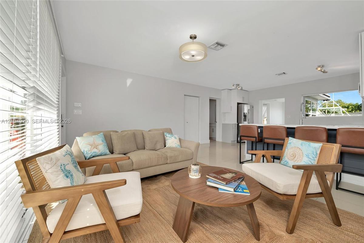 Open-concept living space featuring high-gloss tile flooring, neutral wall tones, recessed lighting, and a breakfast bar with built-in cabinetry