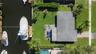Waterfront lot featuring a private boat dock, concrete patio, expansive lawn, and mature palm trees