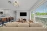 Open-concept interior featuring large-format floor tiling, custom white cabinetry, a spacious kitchen island with stone surfacing, and expansive floor