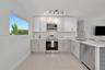 Kitchen featuring shaker-style cabinetry, stainless steel appliances, light-toned stone-finish countertops, tile flooring, and multi-directional track