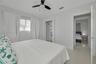 Neutral-toned interior featuring oversized tile flooring, a ceiling fan with integrated lighting, a built-in closet shelving system, and horizontal wi