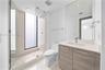 Full-height frameless glass shower enclosure with integrated window, wood-finish vanity with stone countertop, rectangular undermount sink, and polish