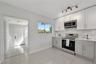 Kitchen featuring white and grey shaker-style cabinetry, stainless steel appliances, polished stone-finish tile flooring, and track lighting