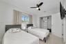 Neutral-toned tile flooring, built-in closet shelving, sliding window with horizontal louvers, and a ceiling-mounted light fixture with fan