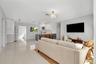 Open-concept interior featuring large-format polished tile flooring, white cabinetry, kitchen island with dark paneling, recessed lighting, and contem