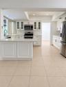 Kitchen featuring white shaker-style cabinetry, a peninsula with stone-finish countertops, stainless steel appliances, and tile flooring