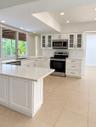 Kitchen featuring white Shaker-style cabinetry, quartz countertops, stainless steel appliances, tile flooring, and glass-paneled upper cabinets