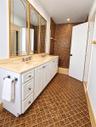 Double vanity featuring white cabinetry, a solid-surface countertop with integrated sinks, and polished metal faucets