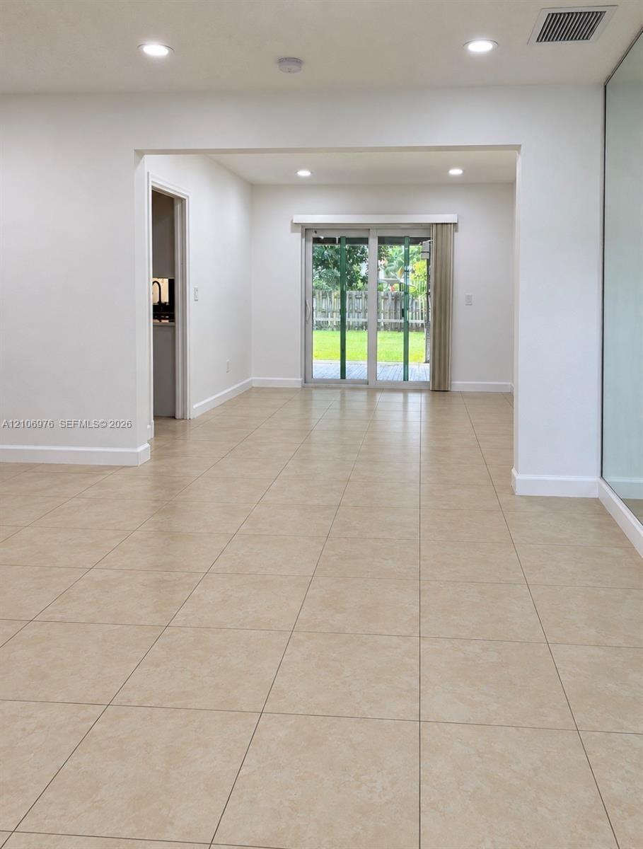 Neutral ceramic tile flooring, recessed lighting, and sliding glass doors leading to a rear exterior space