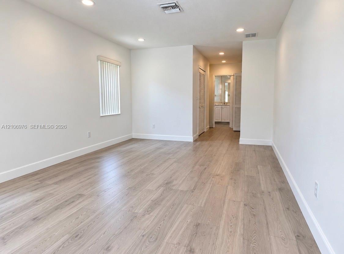 Interior space featuring wood-finish flooring, recessed lighting, and a window with vertical blinds