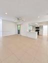 Spacious open-concept living area featuring neutral tile flooring throughout, recessed ceiling lighting, and a ceiling fan