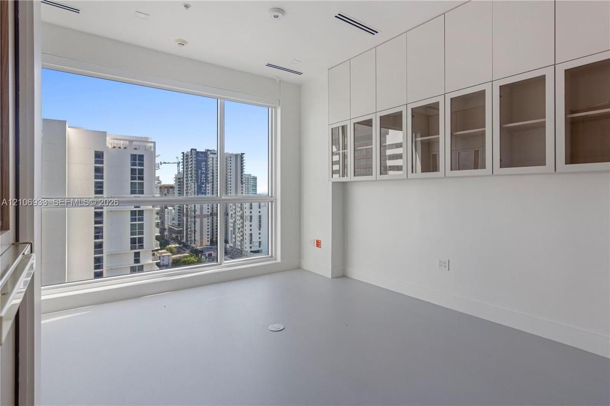 Floor-to-ceiling windows, extensive wall-to-wall built-in cabinetry featuring glass-front upper storage, and smooth-finish flooring
