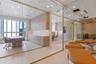 Floor-to-ceiling glass partitions, custom wood-finish cabinetry, built-in storage units with integrated countertops, large-format tile flooring, and r