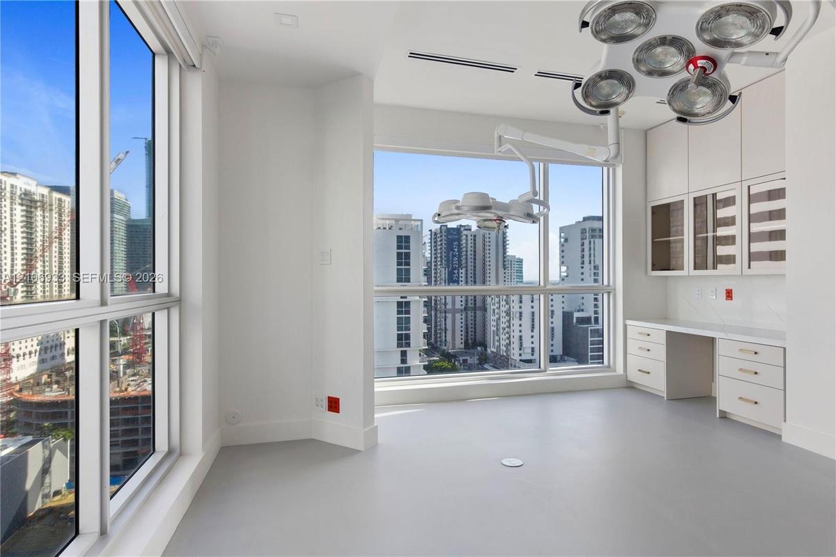 Floor-to-ceiling windows, built-in cabinetry with glass-front uppers, integrated desk surface, ceiling-mounted adjustable lighting fixtures, and solid