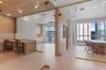 Frameless glass partitioning, slatted wood ceiling, neutral-toned large-format floor tiles, built-in cabinetry with stone surfacing, and integrated re