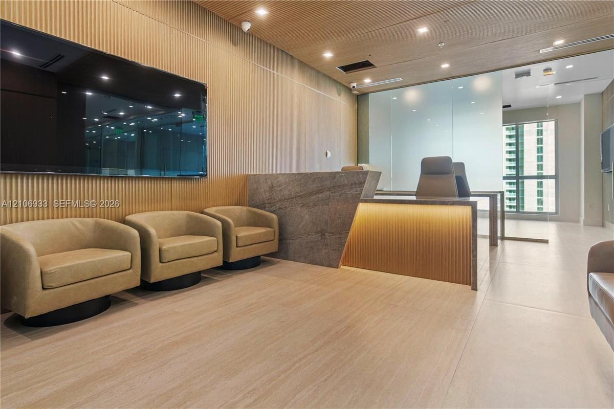 Reception area featuring vertical wood-slatted wall paneling, a large stone-finish service desk with integrated under-counter lighting, matching wood-