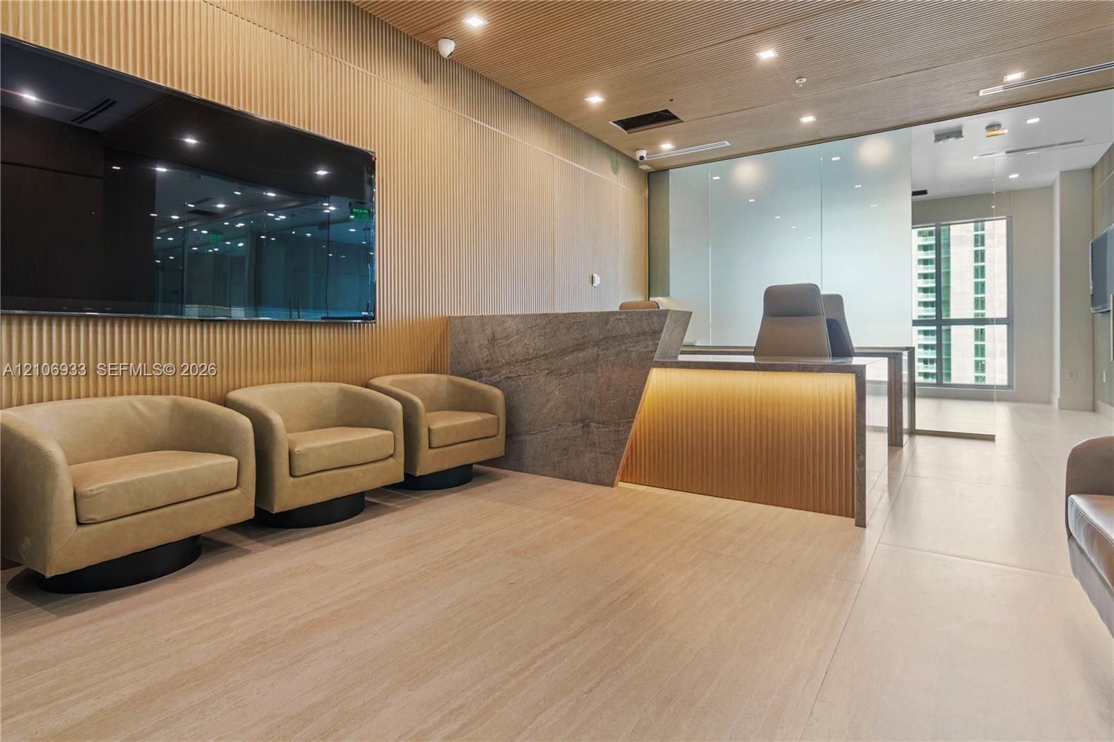 Reception area featuring vertical wood-slatted wall paneling, a large stone-finish service desk with integrated under-counter lighting, matching wood-