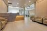 Reception area featuring wood-panelled walls, light-toned tile flooring, recessed ceiling lighting, and a geometric stone-surfaced desk with integrate