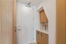 Built-in cabinetry featuring light wood-finish doors, stone-surface countertop, integrated sink, brushed gold-tone faucet, and floor-to-ceiling vertic