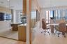 Floor-to-ceiling glass wall partitions, wood-finish flooring, custom wood-veneer cabinetry, quartz-surface countertops, and recessed ceiling lighting