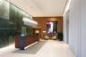 Expansive lobby featuring a large-format green stone feature wall, wood-paneled accents, custom linear pendant lighting, polished flooring, and floor-