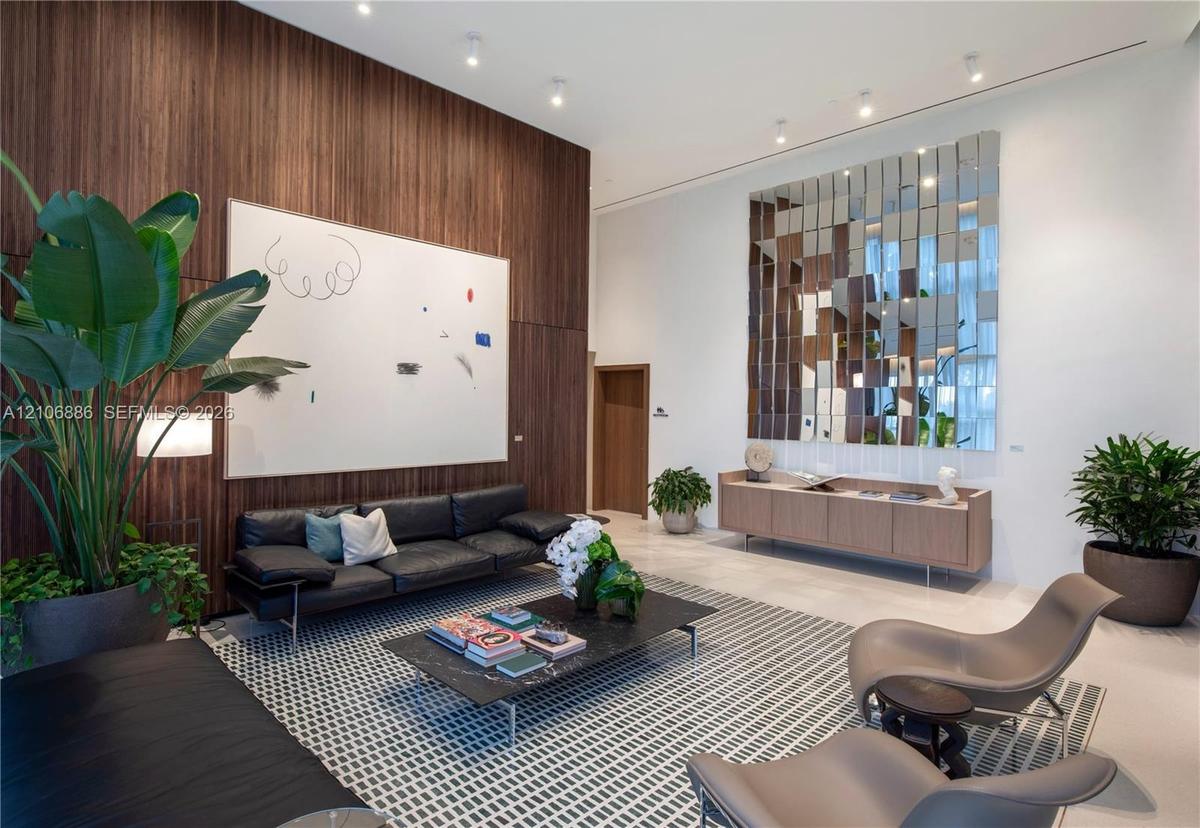 High-ceiling interior featuring a floor-to-ceiling wood-panel accent wall, recessed lighting, polished stone flooring, and a decorative mirrored wall 