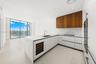 Modern kitchen featuring matte white cabinetry, wood-finish upper cabinetry, stone-surface countertops with matching backsplash, built-in wine refrige