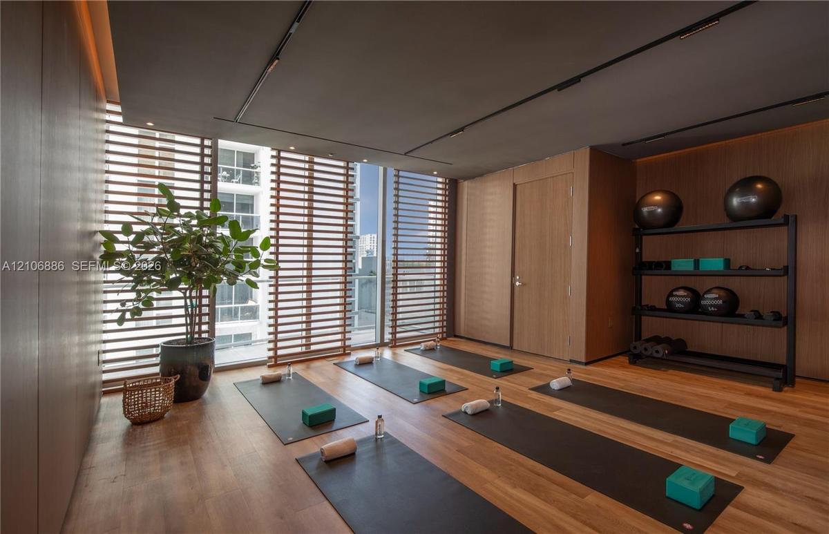 Wood-finish flooring, floor-to-ceiling windows with integrated horizontal slat screening, and wall-to-wall wood-paneling featuring recessed ceiling tr