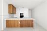 Kitchen featuring a center island with a stone-finish countertop and waterfall edge, two-tone wood-finish and flat-panel cabinetry, built-in wall oven